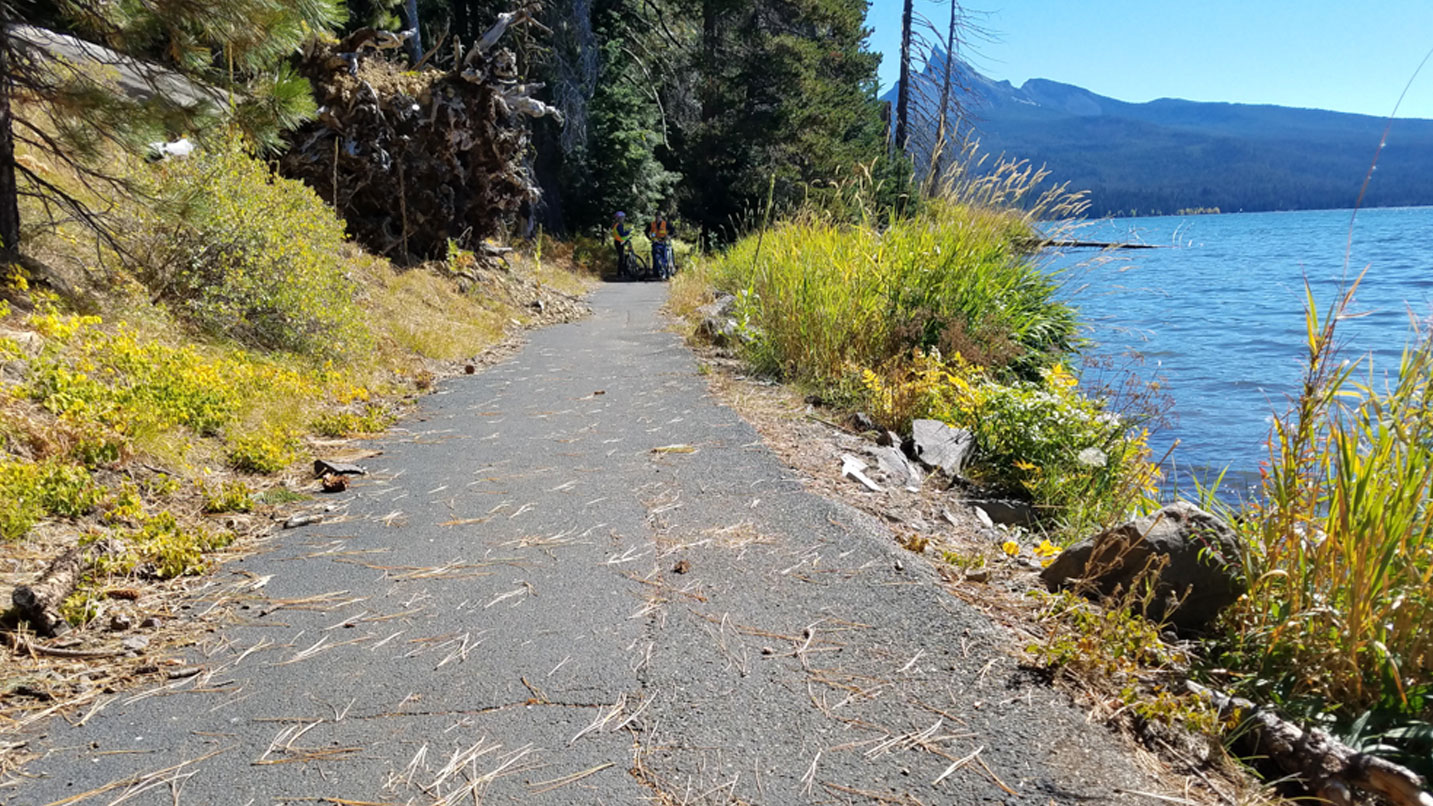 A concrete trail along a lake.
