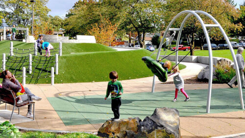 A sensory playground with prominent swing filled with children and parents.