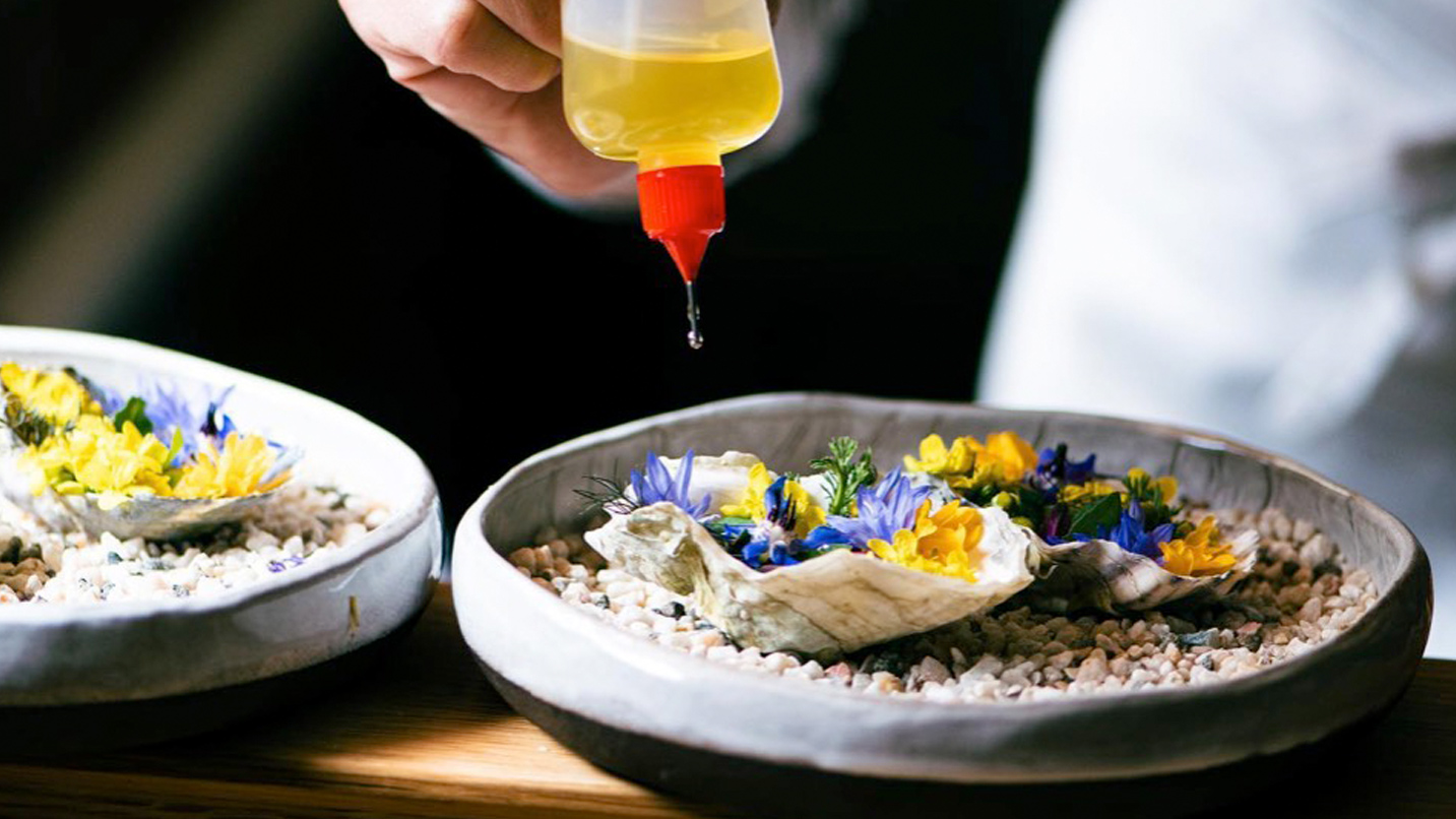 a fancy plate of food, possibly large clams with edible flowers