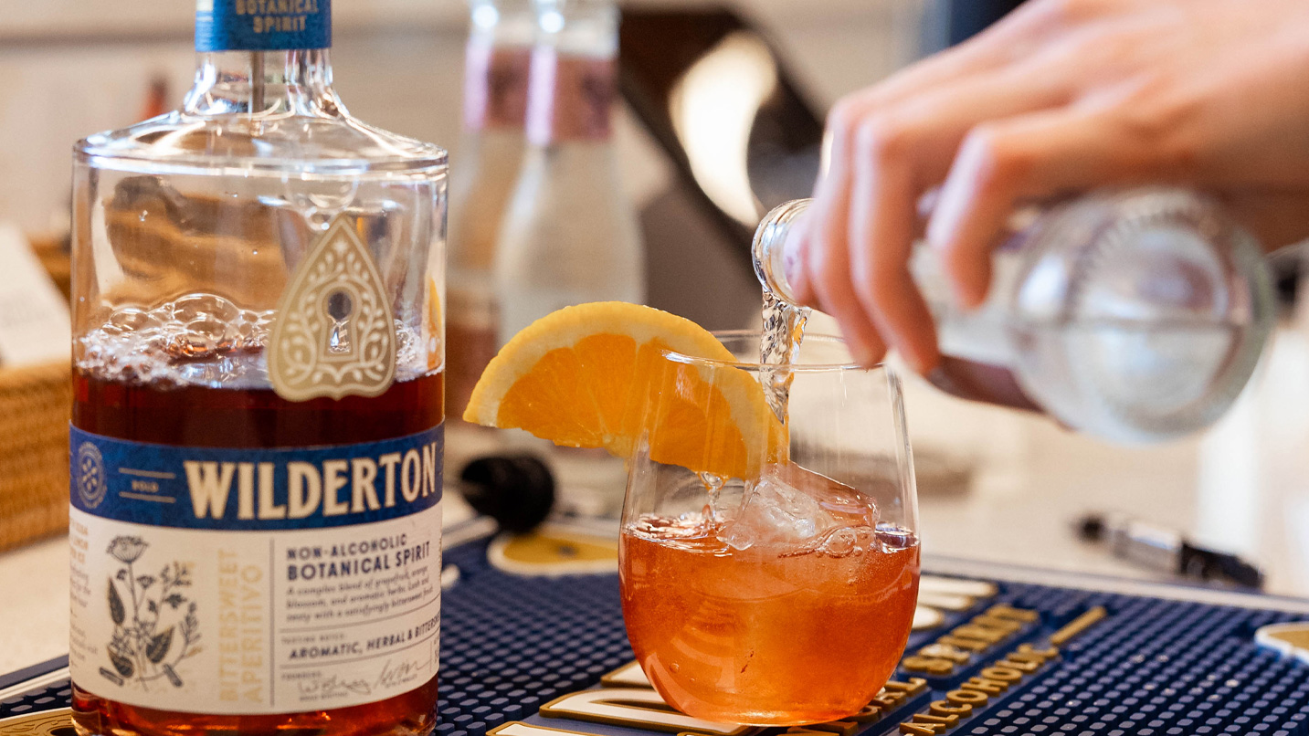 A bottle of Wilderton spirit being poured into a cocktail.