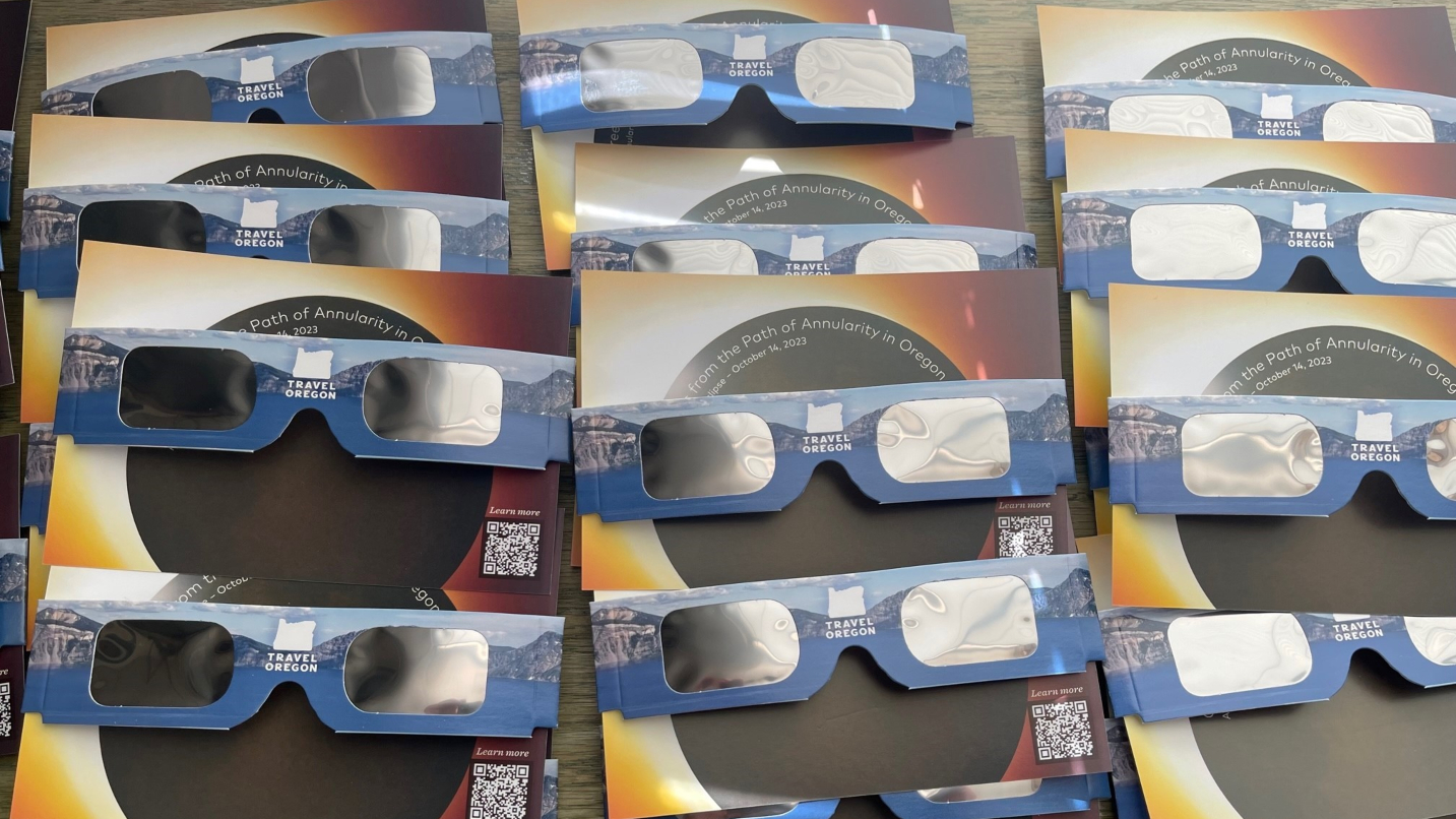 Three rows of eclipse-viewing glasses with Travel Oregon logo in center