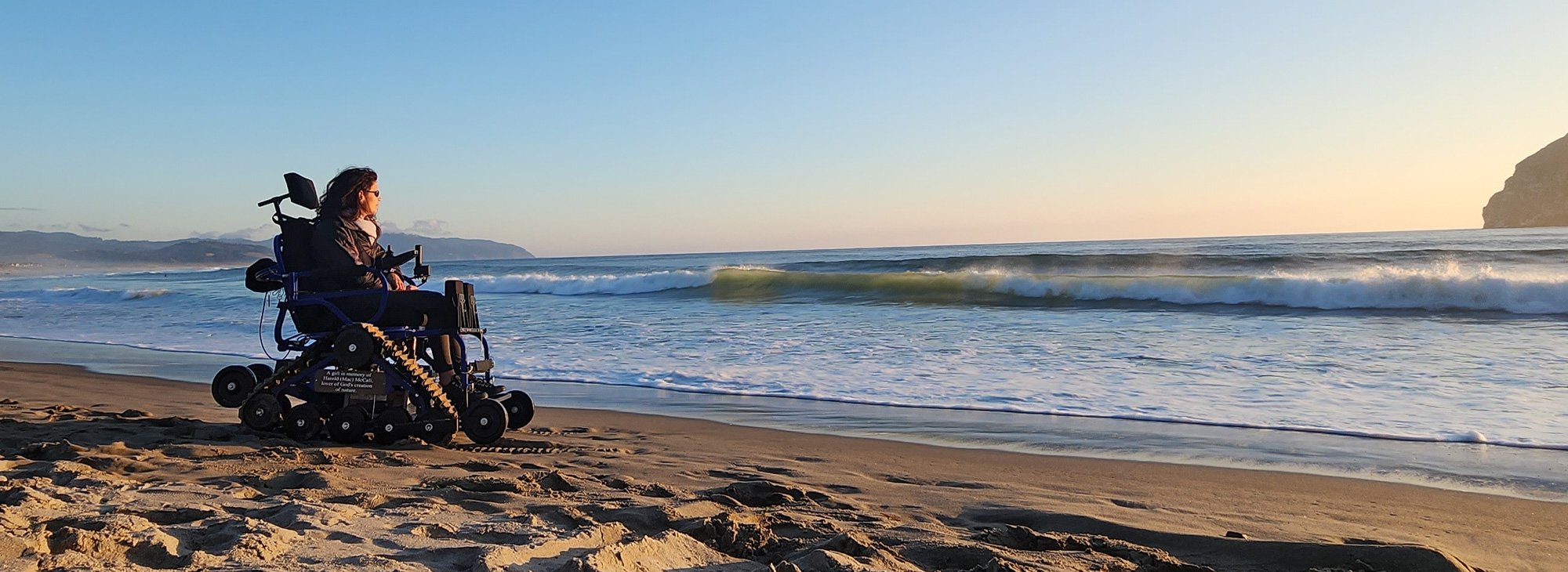 Woman in a wheelchair enjoys sunset on the beach in Oregon.
