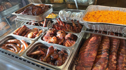 Ready to be served sausages, chicken, racks of ribs and mac and cheese.