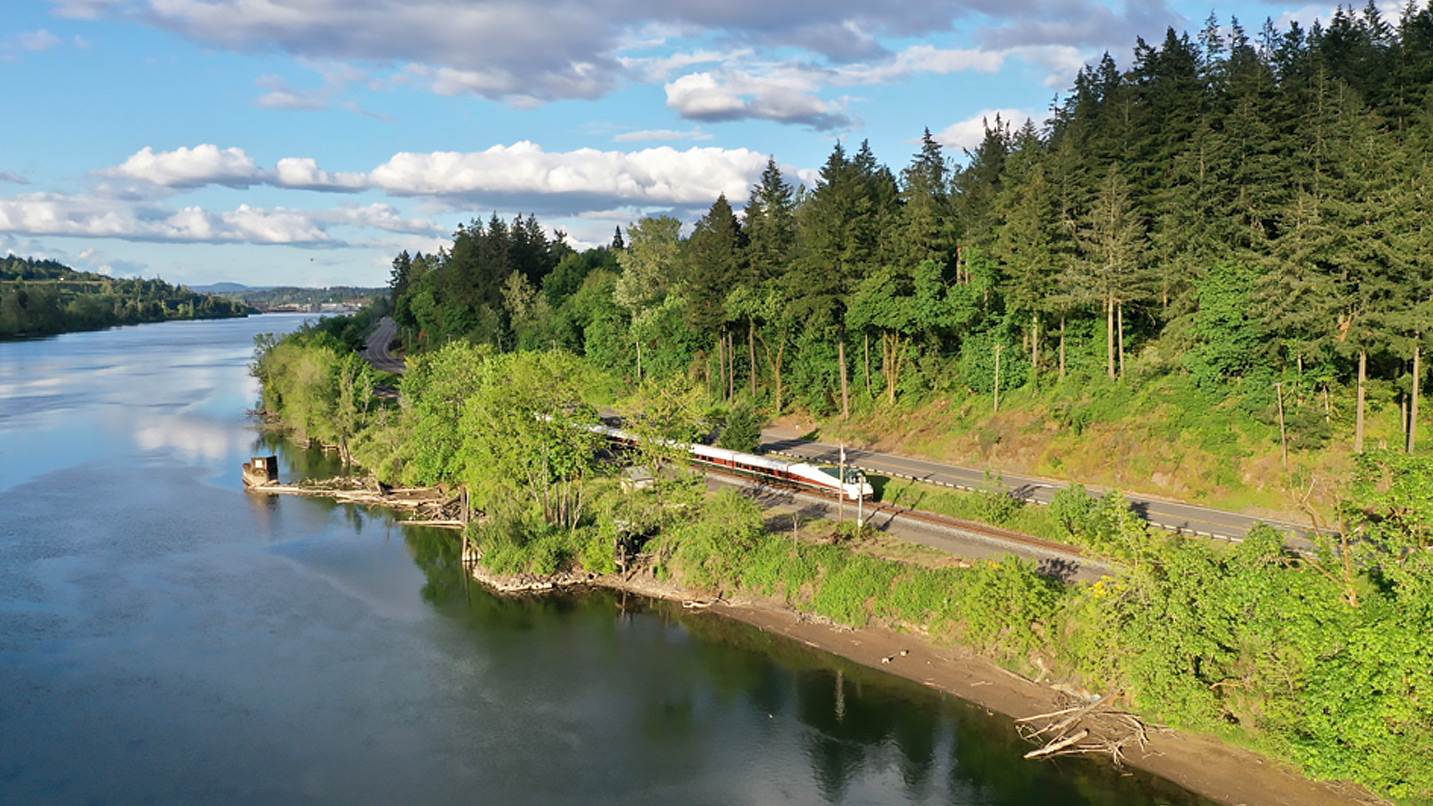 Aerial view of a train and it runs along a river.