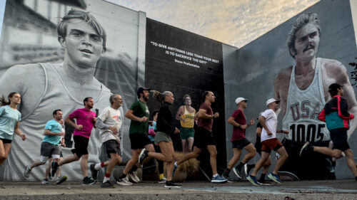 runners pass by huge murals of Steve Prefontaine