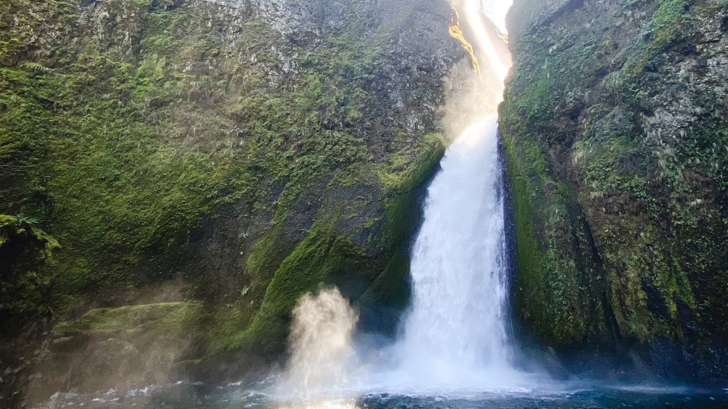 Wahclella Falls, a large waterfall spouts between two large cliff formations.