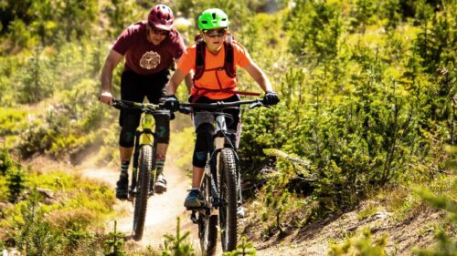 Two people ride mountain bikes on dirt trail