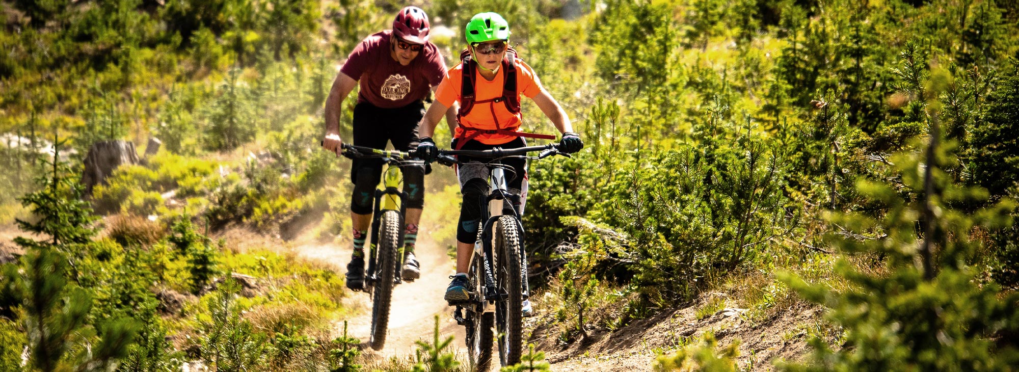 Two people ride mountain bikes on dirt trail