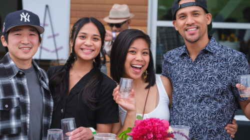 Four people smiling at camera holding stemless wine glasses