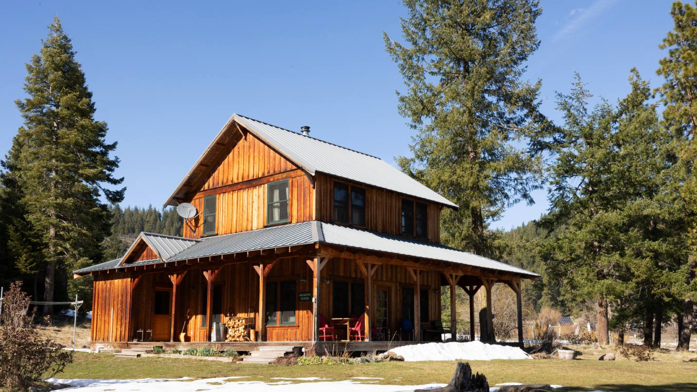 A large wood ranch home on farm land on a sunny day.