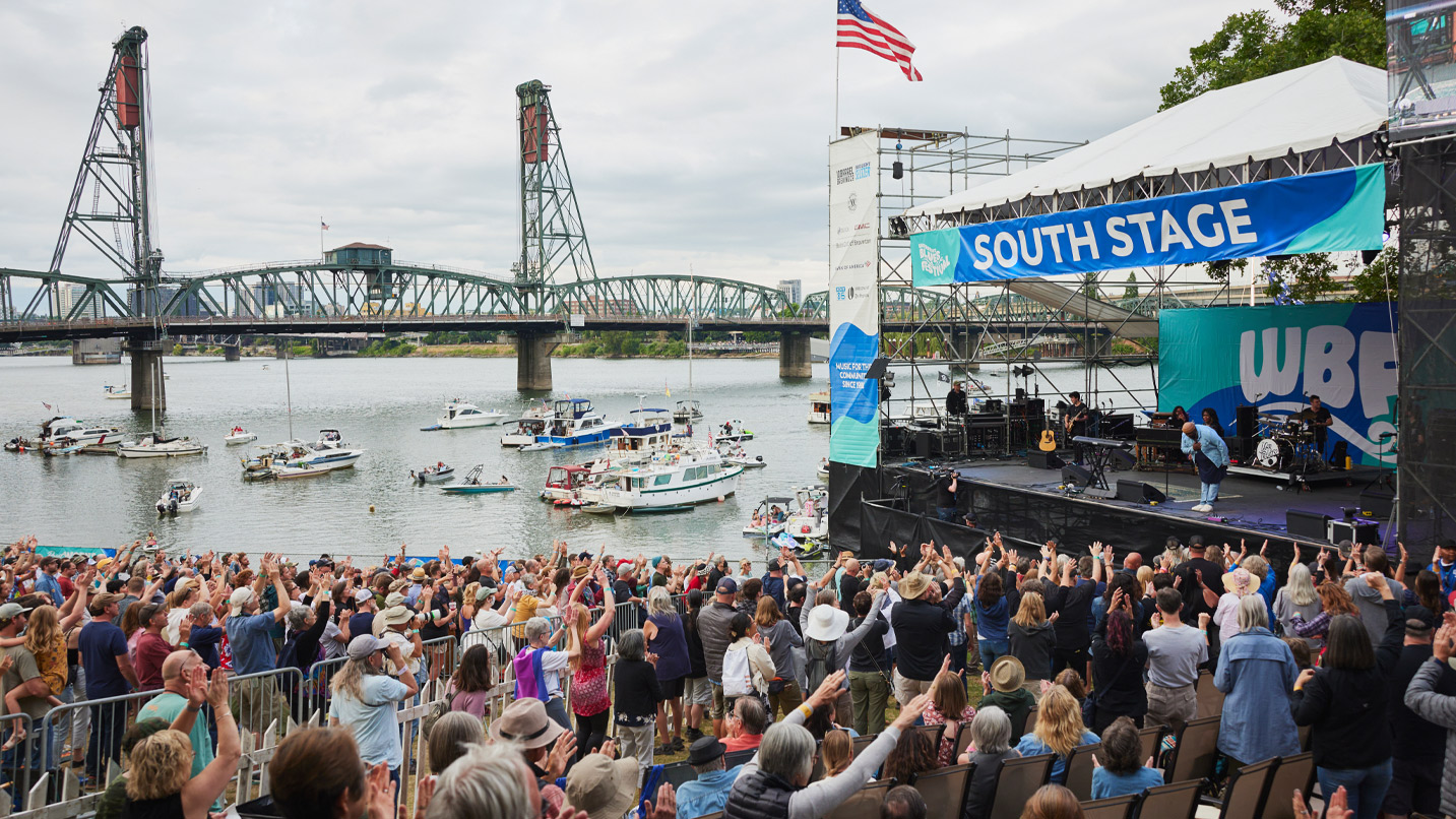 Blues musicians performing to an audience on land and on boat at the Portland waterfront.