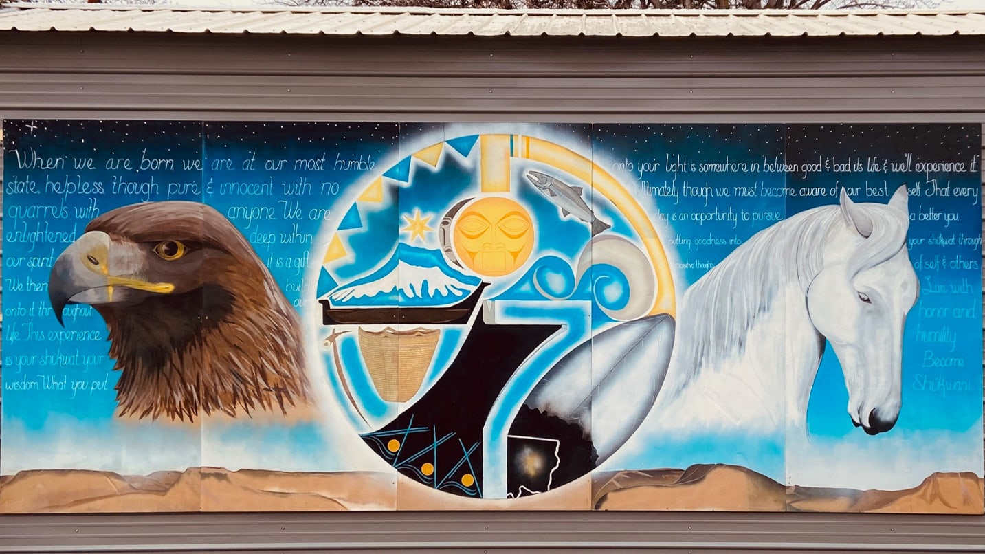 Mural depicting an eagle and a horse flanking a circular design with abstract elements. Background features text: "When we are born, we are at our most humble state...Live with honor and humility. Become Shikwanni."