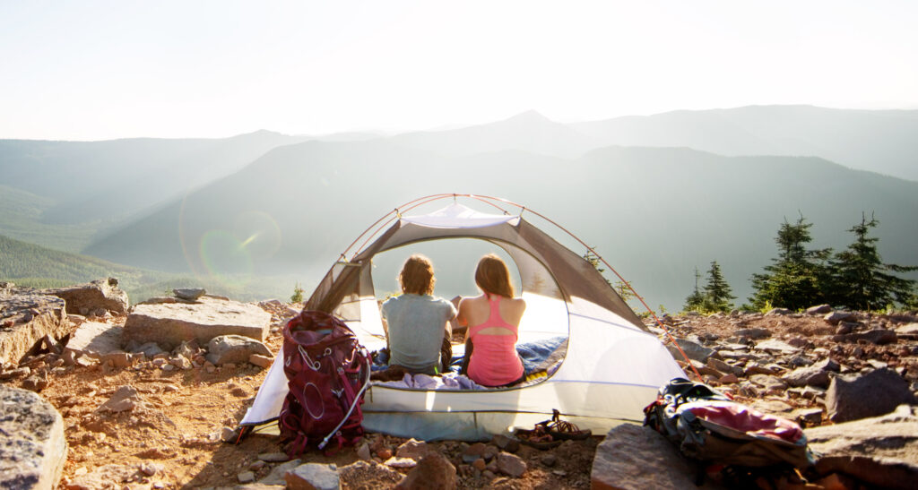 Two women sitting in an open tent viewing the view in front of them.