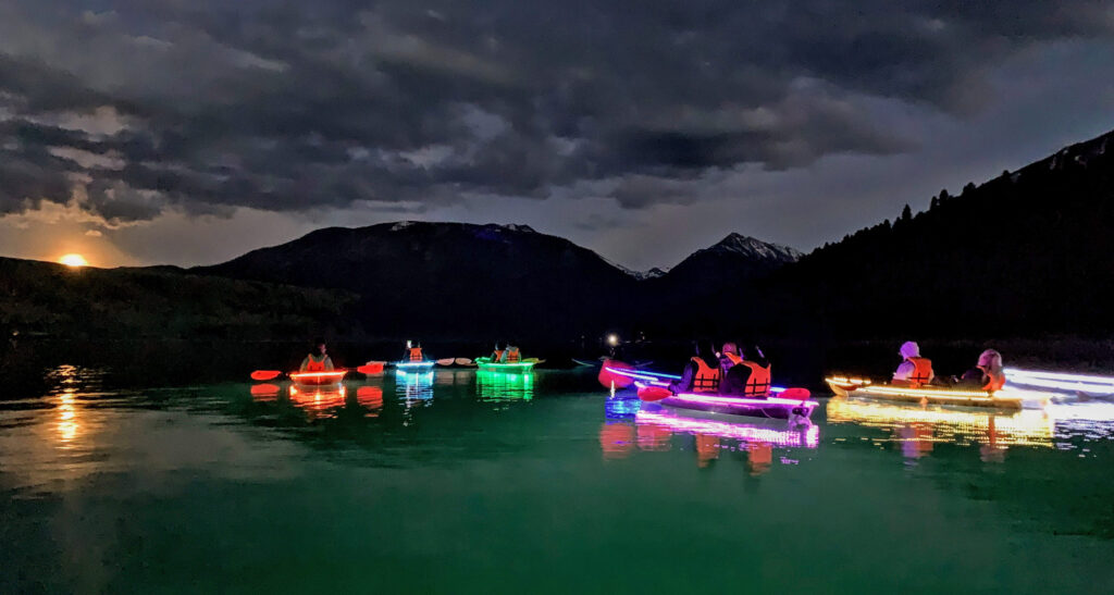 People in light up kayaks enjoying night sky