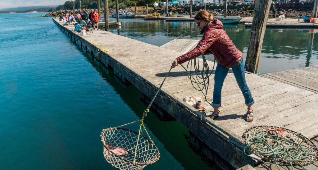Woman drops baited crab pot from dock.