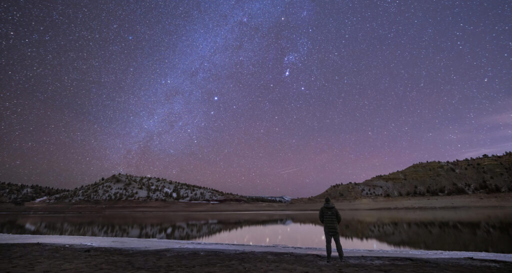 Stars light up night sky with a person observing