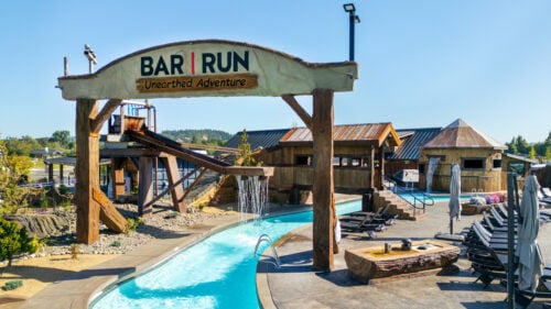 A pool's lazy river water feature flows underneath a sign.