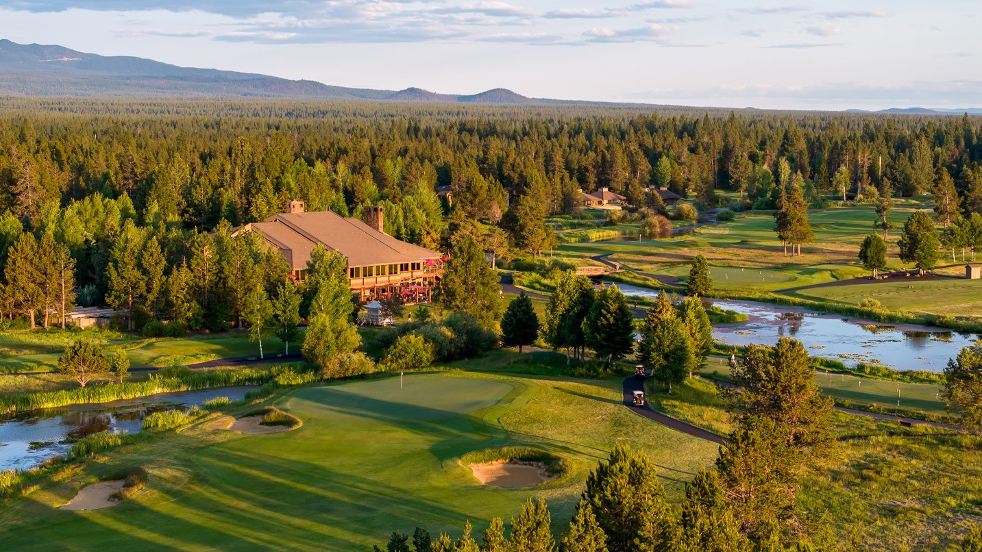 An aerial view of a golf course with mountains in the distance.