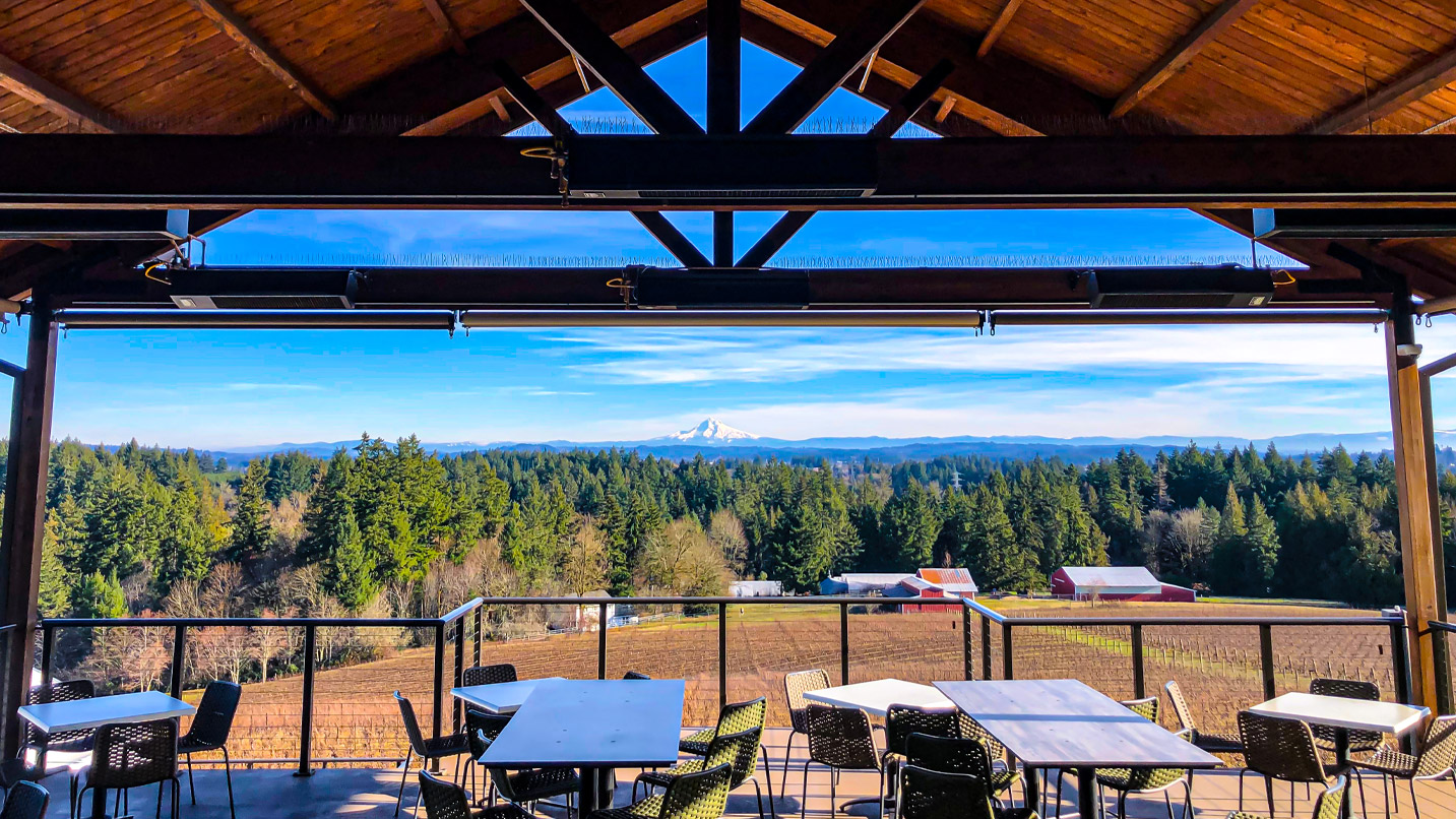 View from the covered top deck of a winery looking out to a mountain.