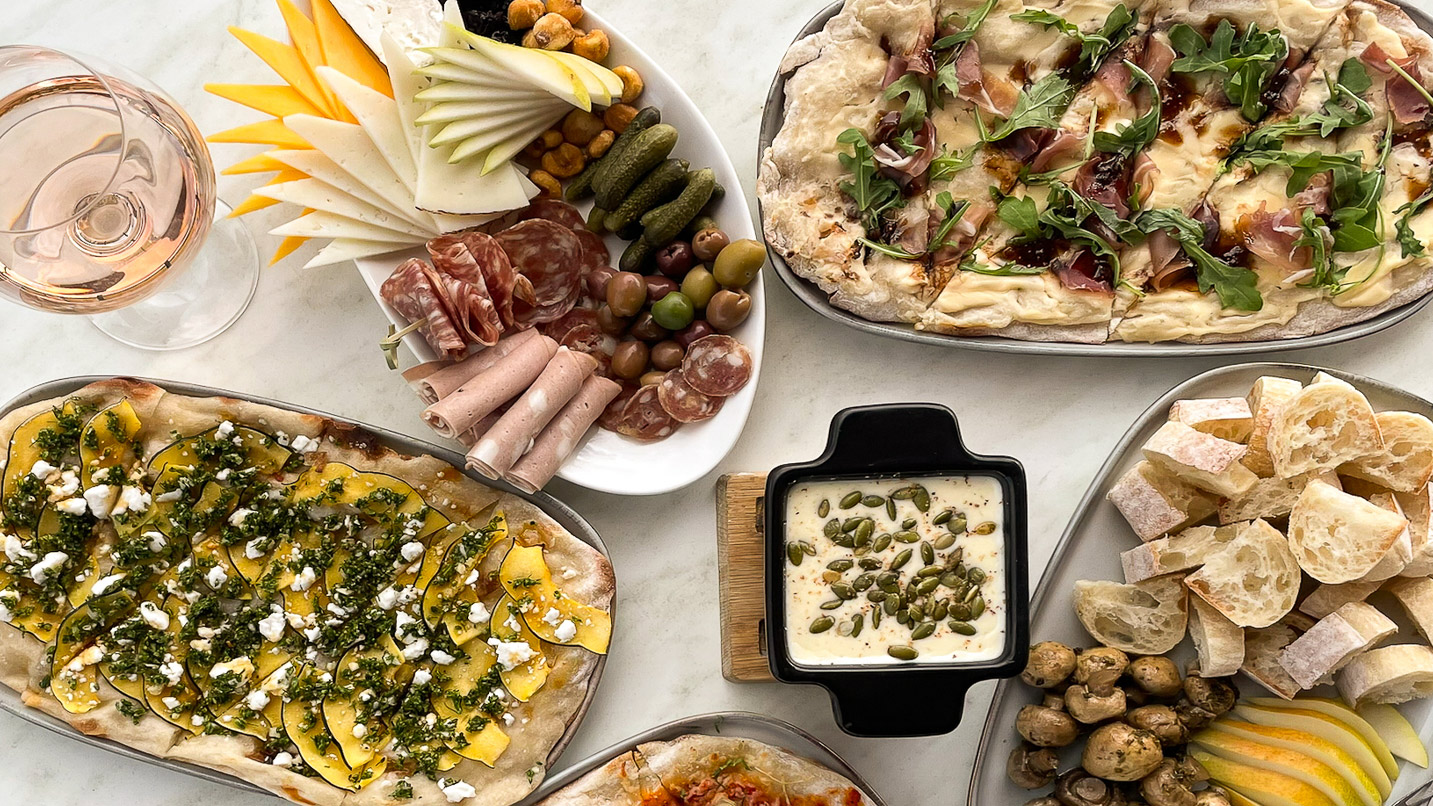 A table with multiple dishes of food and wine.