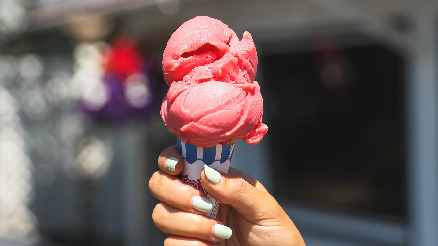 Two scoops of strawberry ice cream on a sugar cone.