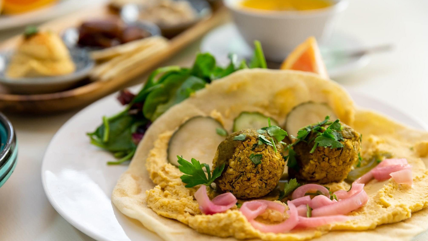 A falafel wrap on pita bread with hummus and Mediterranean fixes.