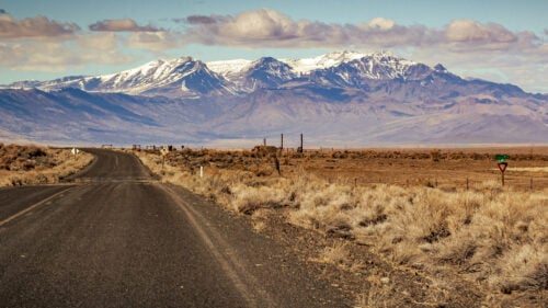 A majestic view of the Steens Mountain, rolling clouds and high desert landscape from a highway road.