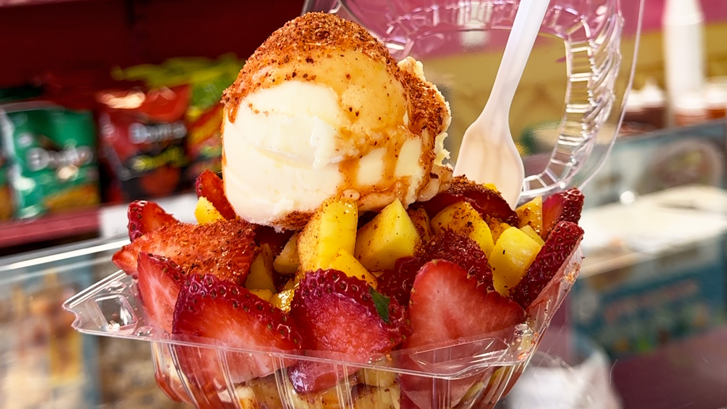 Strawberries, mangoes and a scoop of ice cream in a containter.