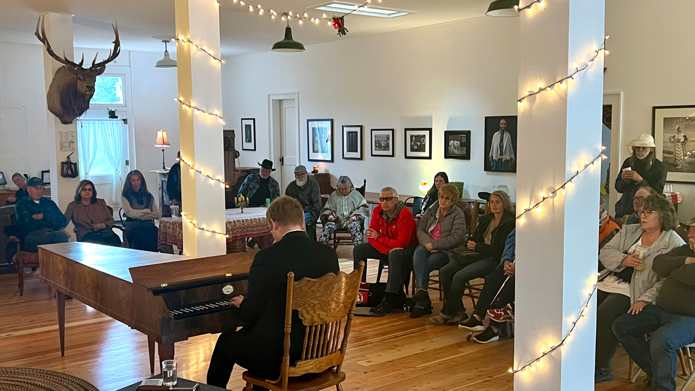 A person plays the piano in front of a small audience.