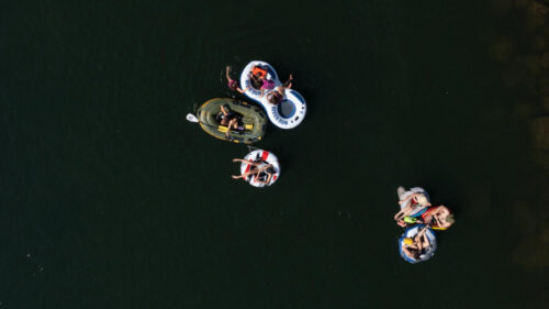 Aerial view of people in inner tubes and a mini raft on a calm day on the Deshutes River near Tumalo State Park.