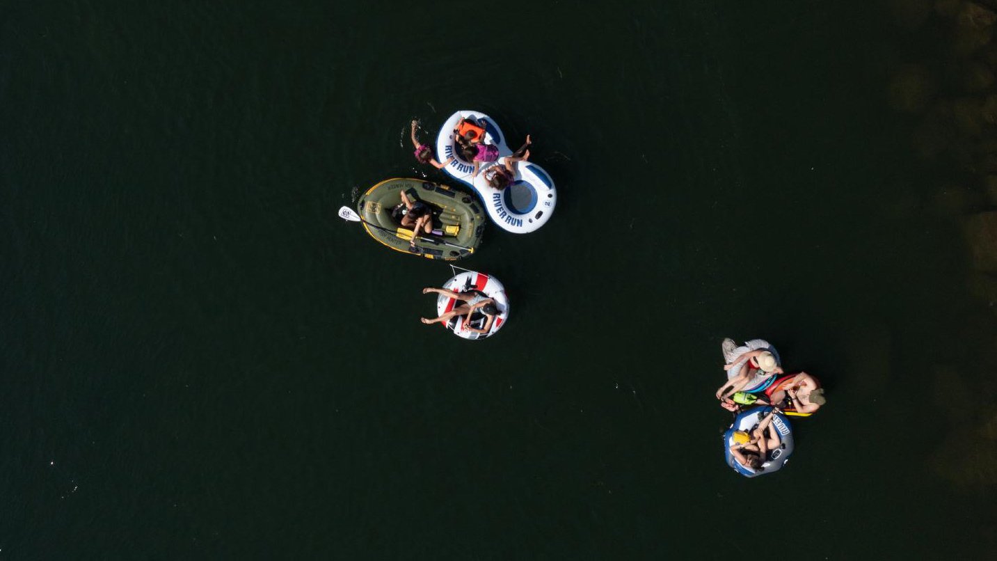 Aerial view of people in inner tubes and a mini raft on a calm day on the Deshutes River near Tumalo State Park.