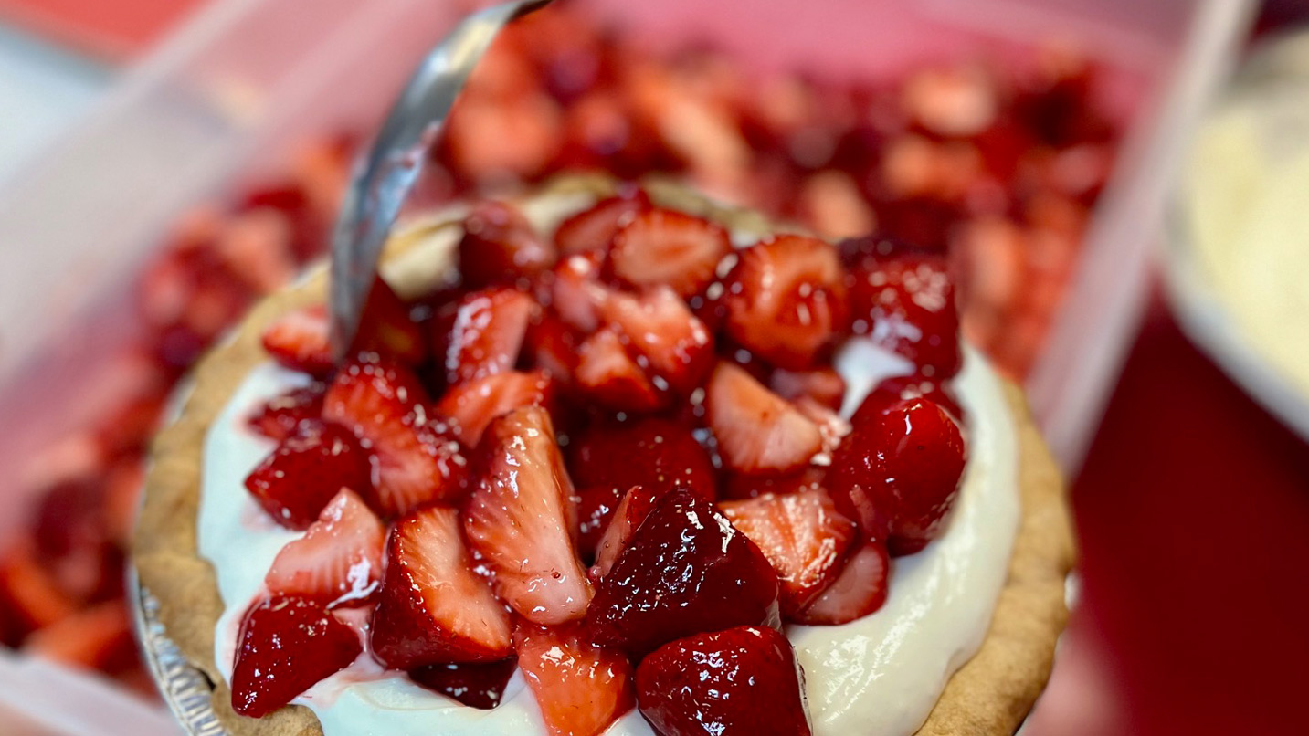 Diced strawberries sit on top of a layer of cream adorning a bread-like cupcake baked good.