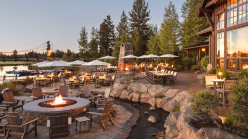 An outdoor dining fire pit outside a window-filled building.