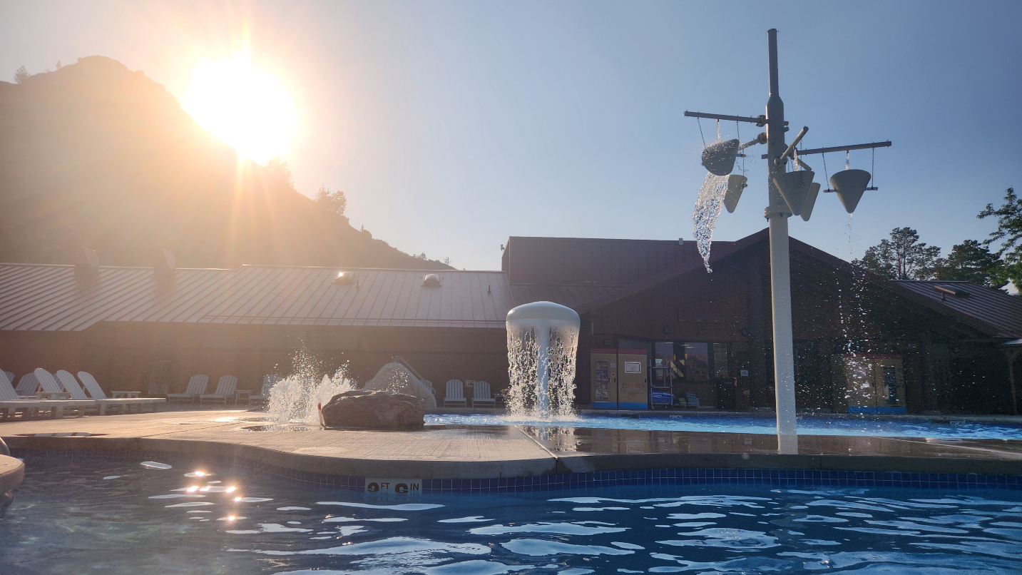 Sunset behind a mountain with a pool and water features in foreground