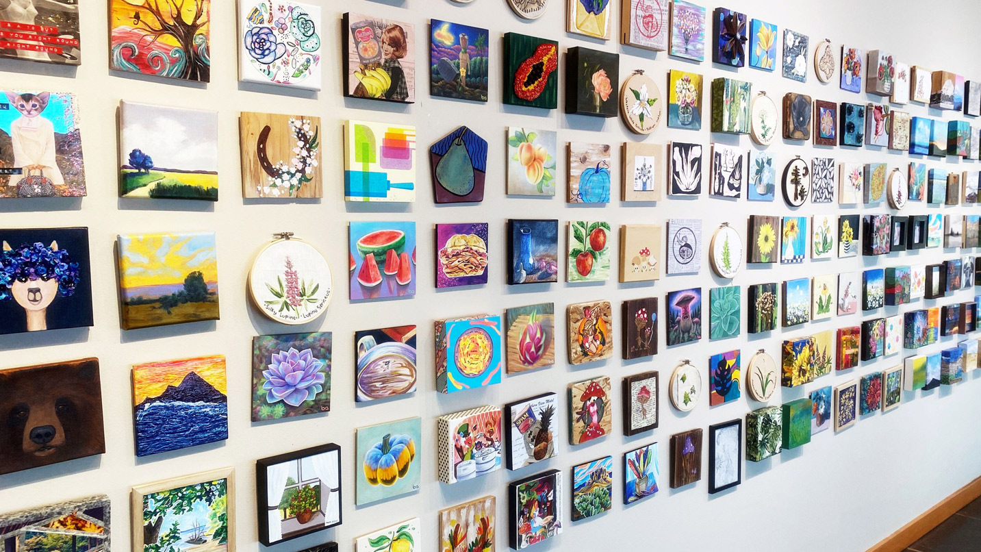 A wall full of small square pieces of art.
