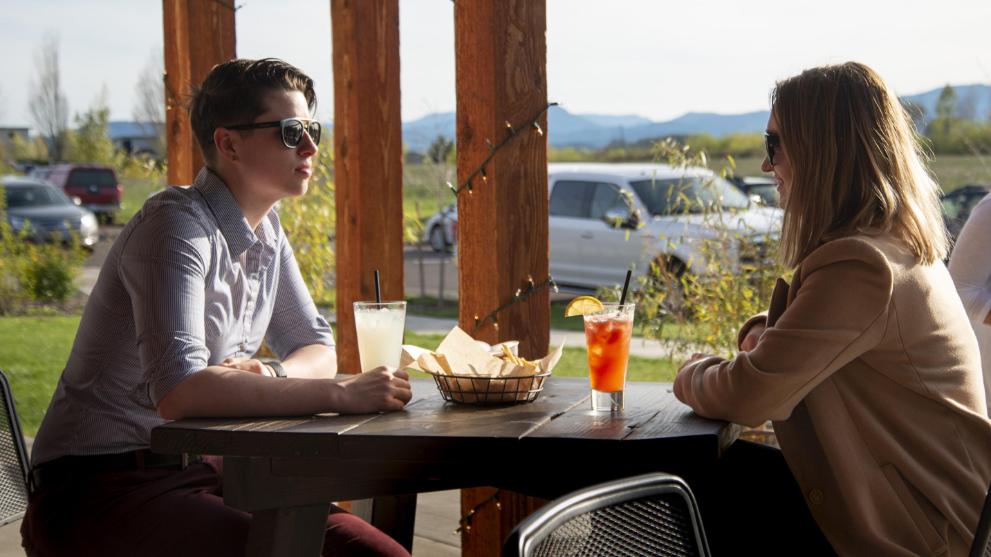 Two people at a restaurant table with drinks and a basket of chips.