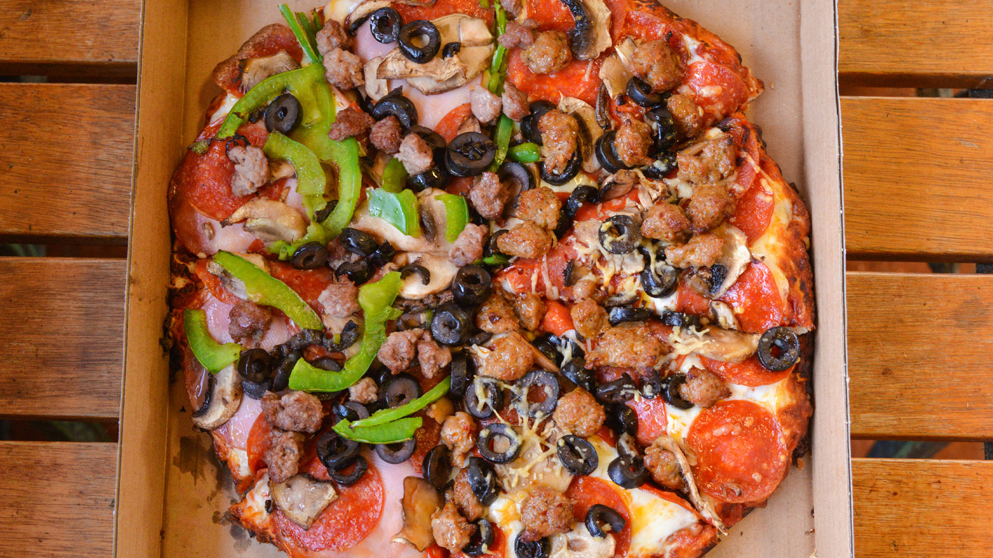 A supreme pizza with all the toppings - cheese, pepperoni, sausage, green bell pepper, olives and mushrooms.