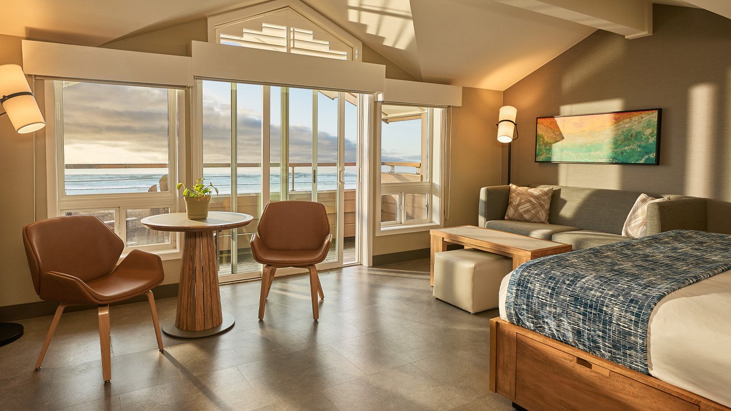 A large room with a balcony overlooking the ocean.
