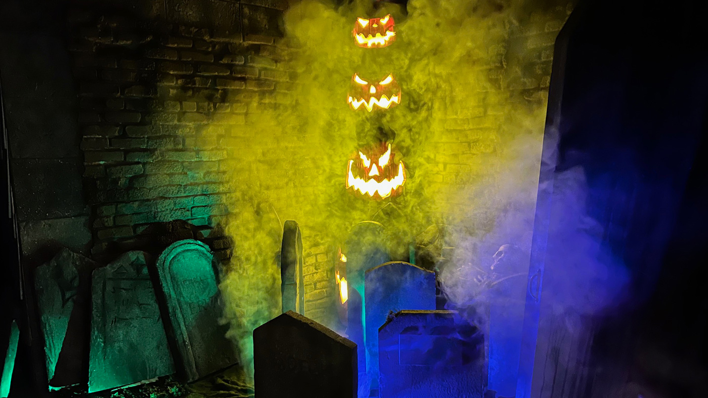 A smokey display of carved pumpkins and tombstones in a haunted house.