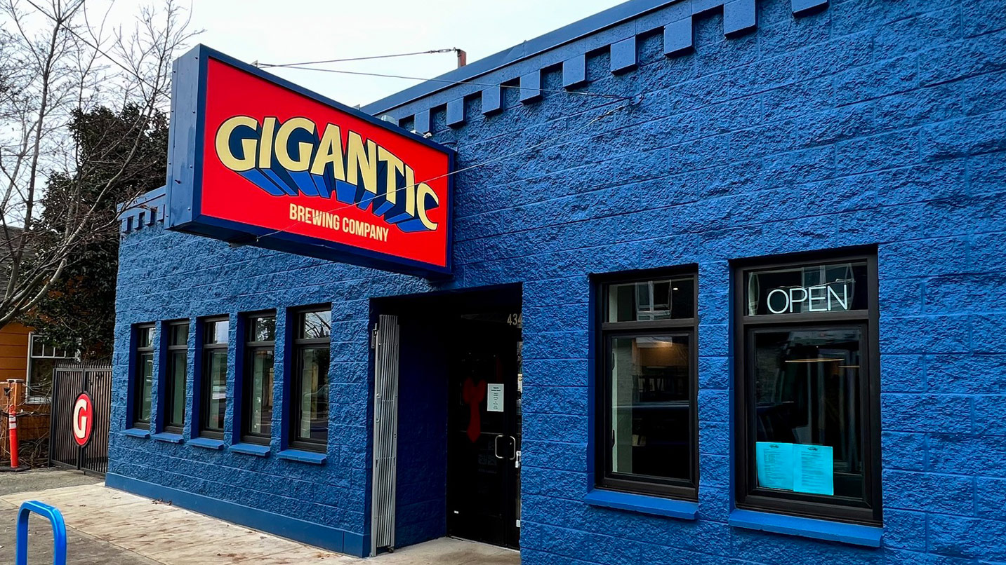 A deep blue building with a sign reading "Gigantic Brewing Company" in stylized font.
