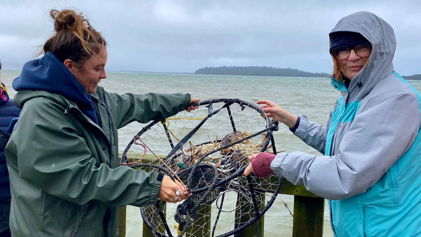 Two women smiling holding a crabbing net.