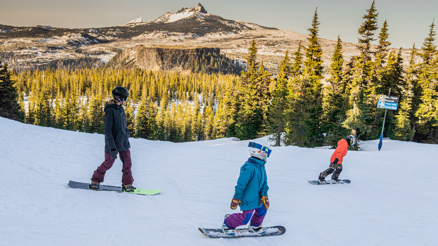 A family snowboards down a mountain.