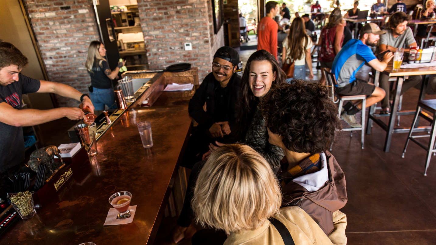 A group of people sitting at a bar in a bustling restaurant.