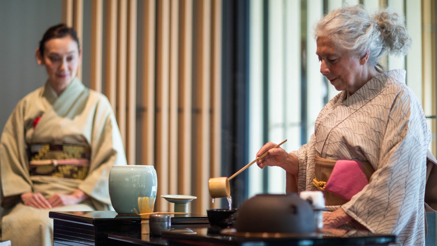 A woman in traditional Japanese clothing pours tea into a cup.