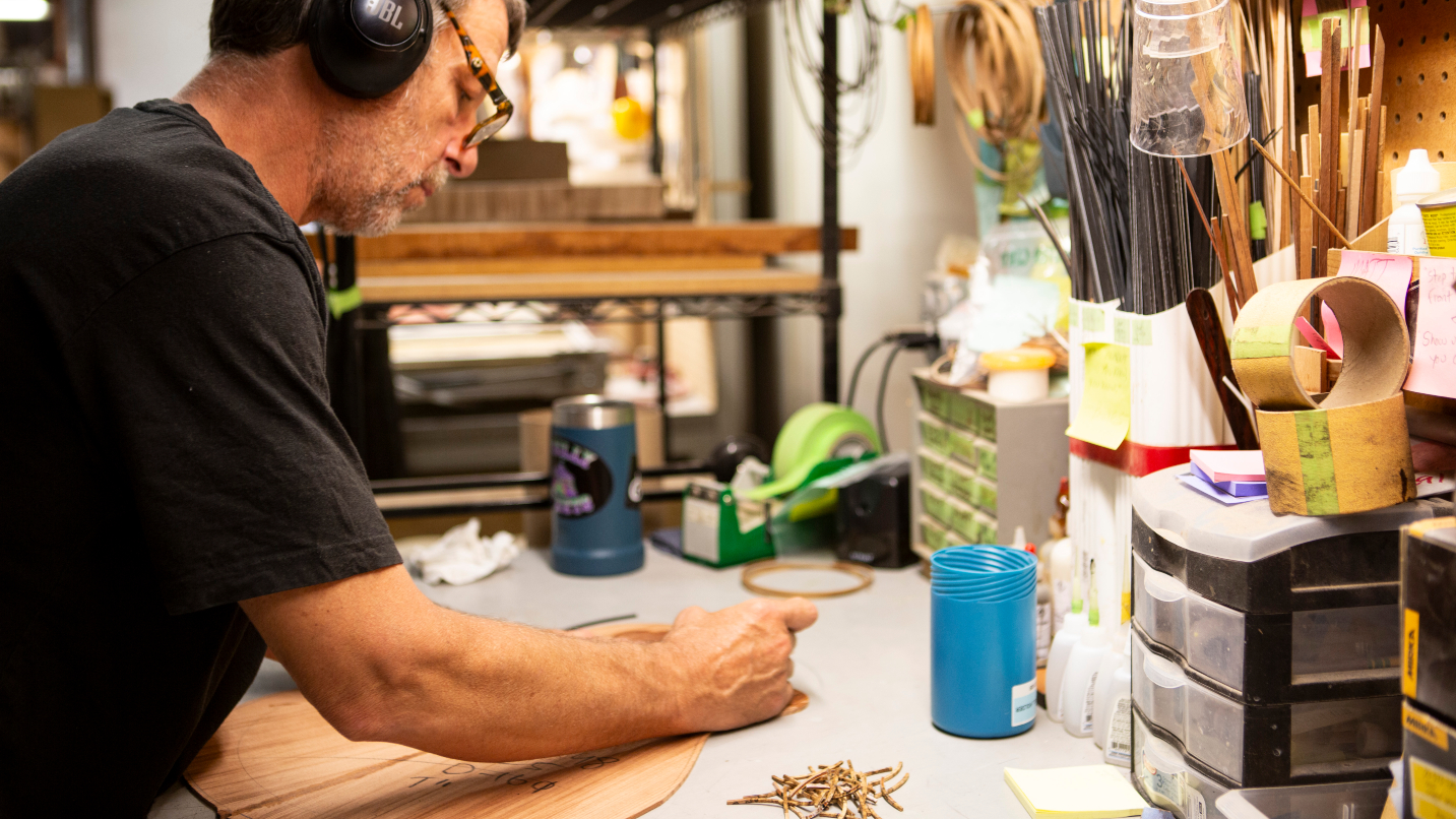 Man with glasses and headphones works on wood project in workshop