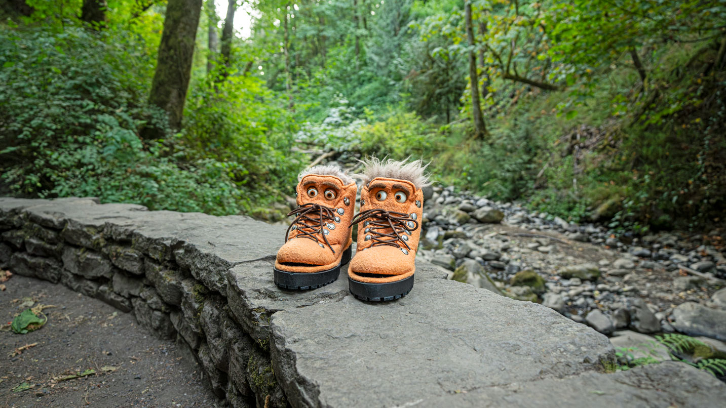 Puppet boots on stone will with creek and trees in background