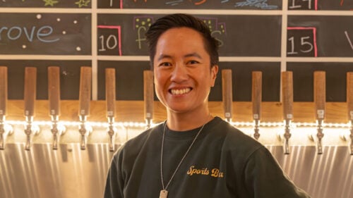 Woman smiles in front of row of beer taps