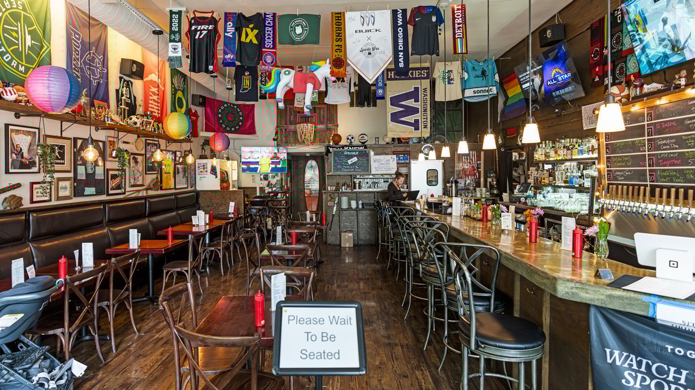 Interior of sports bar with sports paraphernalia, tables and chairs and a bar