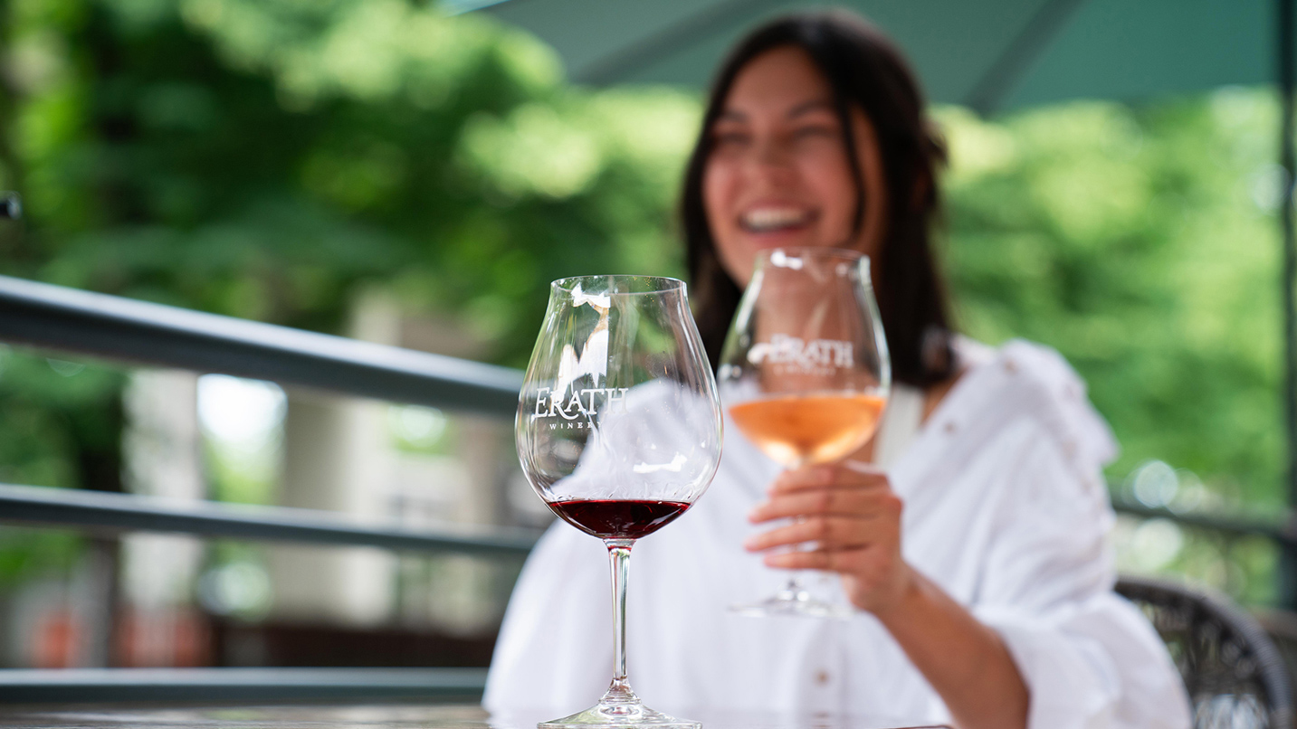 A person sits outside holding a glass of rose-colored wine.