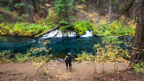 Two people overlooking a waterfall into a river.